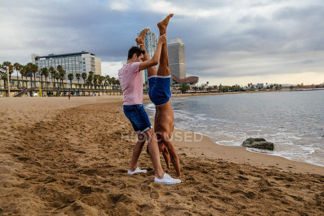 Deux athlètes font un handstand sur la plage — Photo de stock