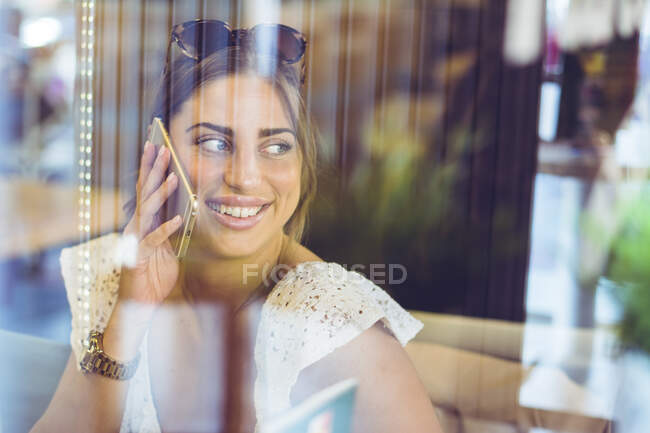 Молодая женщина разговаривает на смартфоне в помещении — стоковое фото