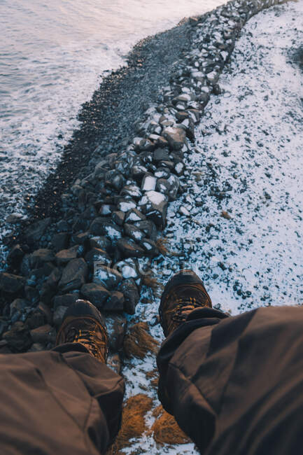 Обрізати ноги над скелястим засніженим берегом — стокове фото