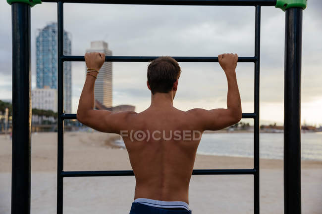 Hombre joven entrenando en bares en el exterior - foto de stock