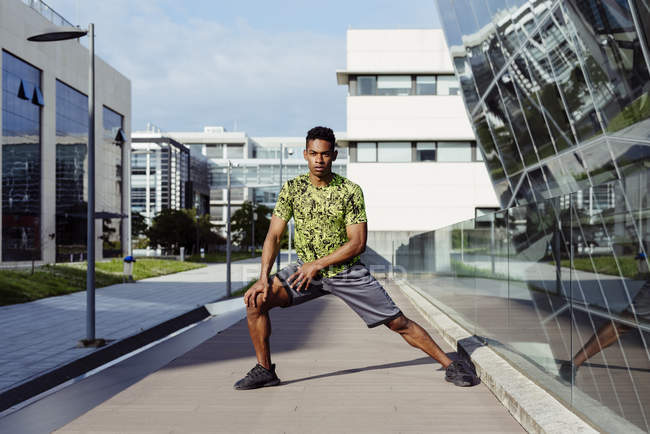 Афроамериканец греет ноги в городе с современными зданиями на заднем плане — стоковое фото