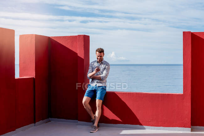 Man seating in a red rooftop building — Stock Photo