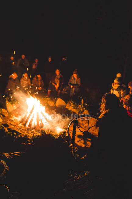 Grupo de personas reunidas alrededor del fuego en los bosques - foto de stock