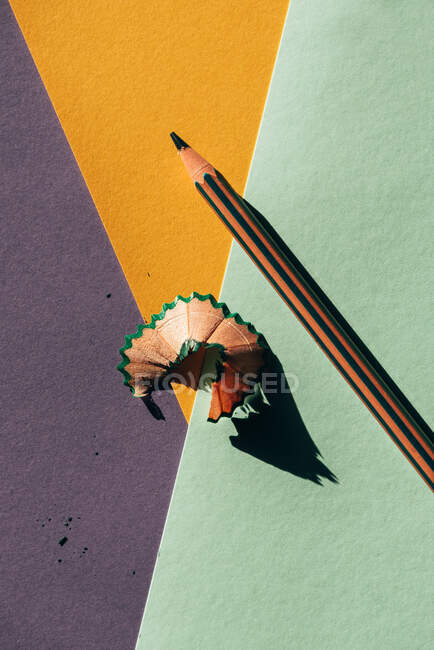 Matita e trucioli da affilatura, su sfondo colorato carte geometriche. Concetto di ritorno a scuola — Foto stock