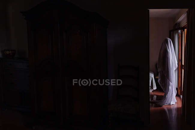 Person disguised as ghost for Halloween walking in house — Stock Photo