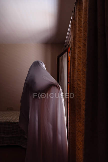 Persona disfrazada de fantasma para Halloween caminando en casa - foto de stock