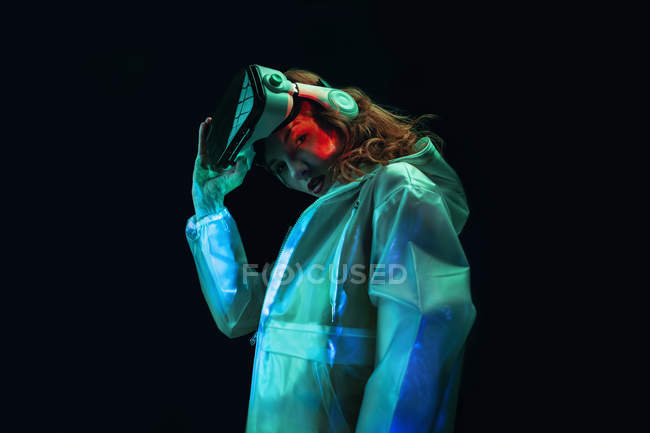 Jovem mulher vestindo óculos VR em luz de néon no fundo preto — Fotografia de Stock