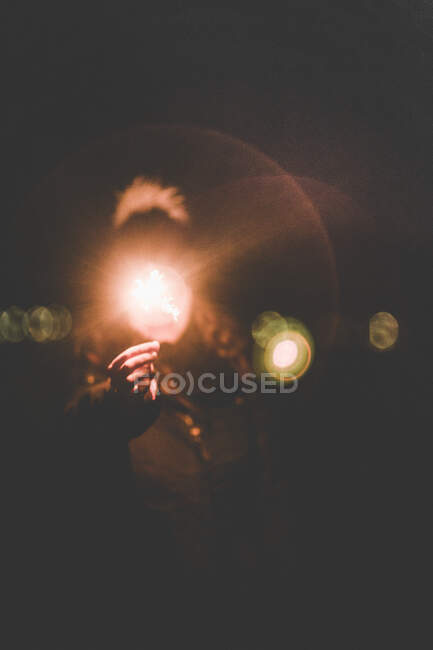 Погляд анонімної людини, що тримає яскравий мерехтливий блиск у темряві — стокове фото