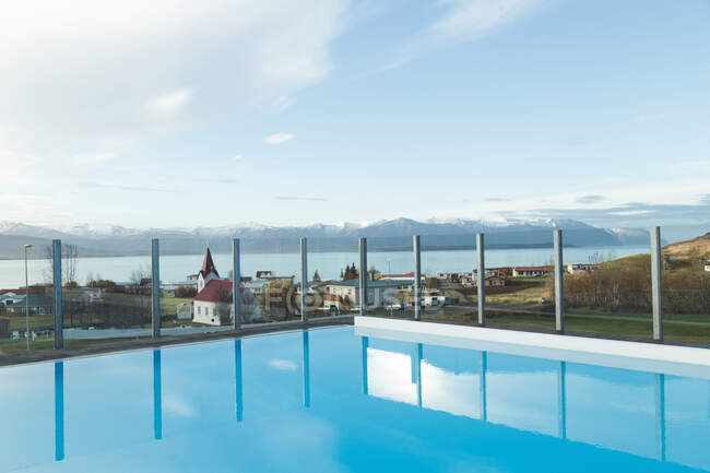 Paesaggio di acqua blu in piscina con lago e montagne sullo sfondo con la luce del sole sopra la piccola città sulla riva — Foto stock
