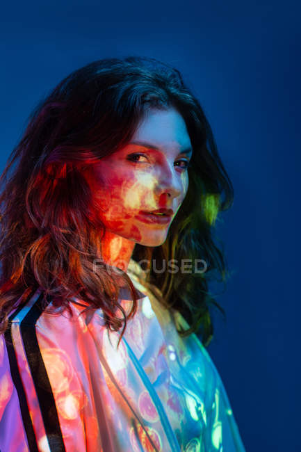 Portrait of young confident woman in stains of neon light — Stock Photo