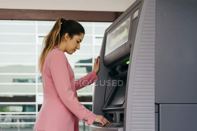 Jeune femme élégante utilisant la machine ATM — Photo de stock