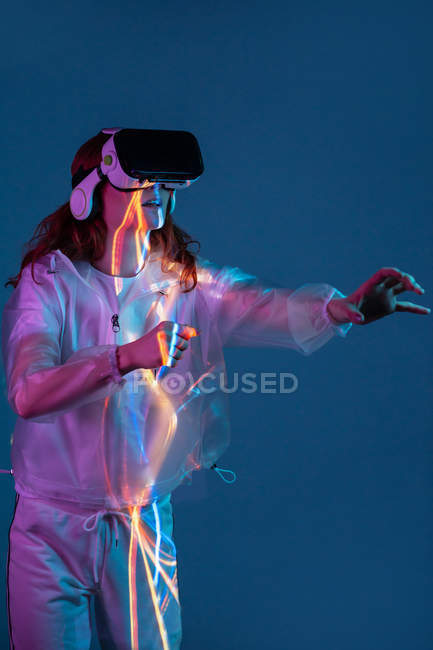 Woman touching air while having virtual reality experience in neon light — Stock Photo
