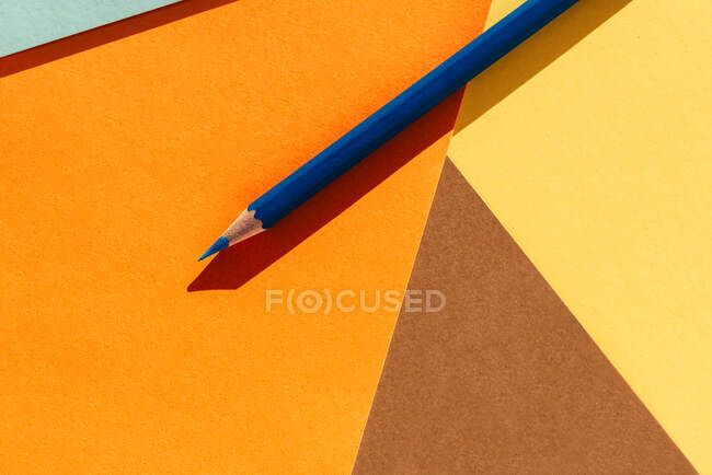 Blue pencil, on light yellow and orange geometric background, back to school concept — Stock Photo