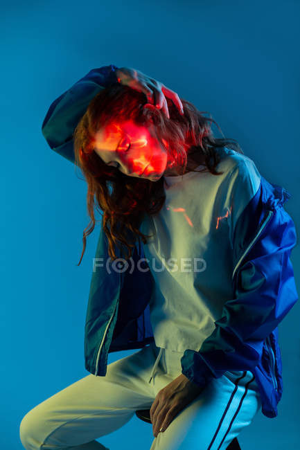 Мрійлива жінка сидить з плямами неонового світла на обличчі — стокове фото