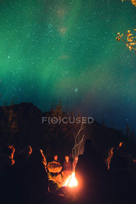 Group of people gathering around fire in woods — Stock Photo
