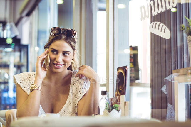 Улыбающаяся женщина слушает сообщение на смартфоне и смотрит в сторону — стоковое фото