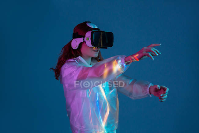 Жінка торкається повітря, маючи досвід віртуальної реальності в неоновому світлі — стокове фото