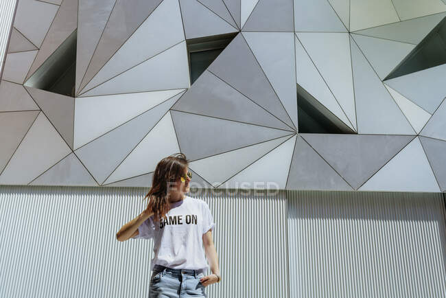 Fröhliche Frau posiert nahe moderner Mauer — Stockfoto