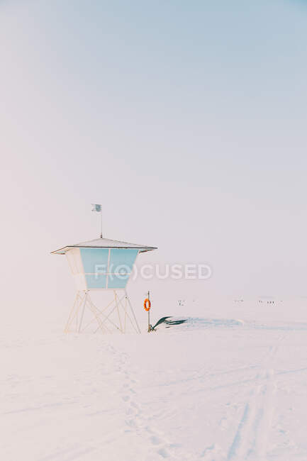 Vista da pequena cabine de praia na costa coberta de neve à luz do sol — Fotografia de Stock