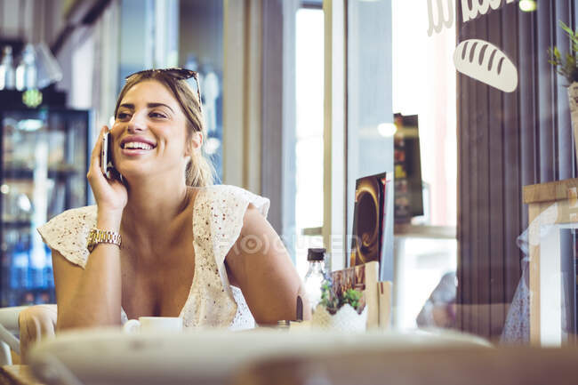 Молода жінка розмовляє по смартфону в приміщенні — стокове фото