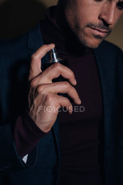 Jeune homme d'affaires dans un studio appliquant du parfum — Photo de stock