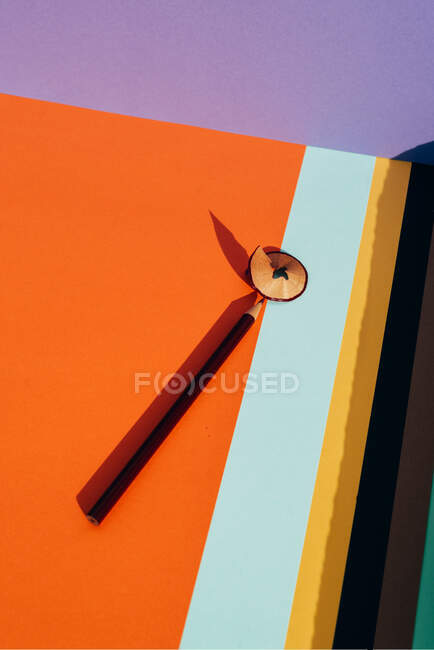 Pencil and shavings from sharpening, on colored striped papers background. Back to school concept — Stock Photo