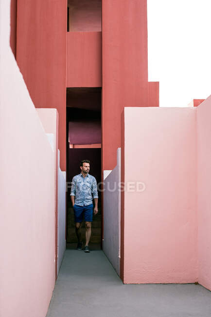 Задумчивый человек, идущий в розовом здании — стоковое фото