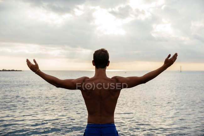Молодий спортсмен позує біля моря — стокове фото