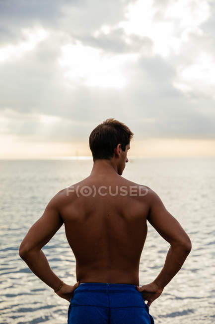 Молодий спортсмен позує біля моря — стокове фото