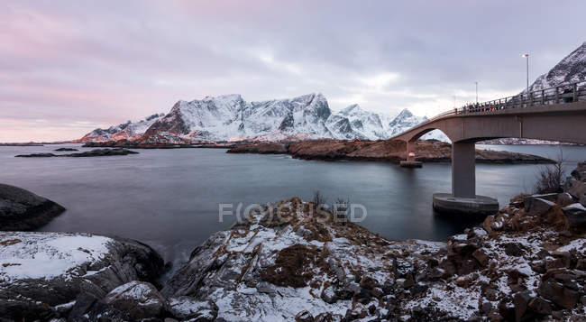 Живописный вид на снежные горы и море на фоне моста — стоковое фото