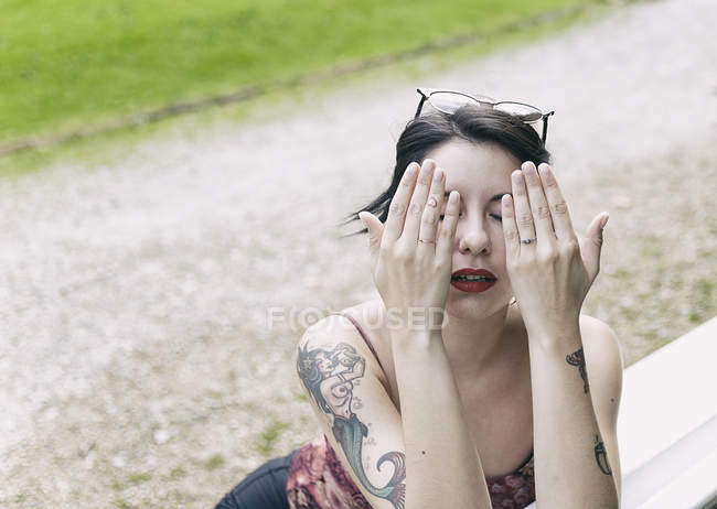 Hipster молода жінка сидить на відкритому повітрі і охоплюють обличчя руками — стокове фото