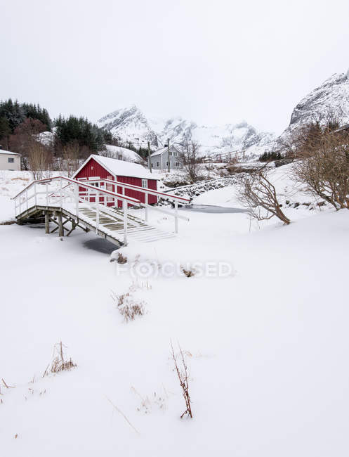 Cabaña roja de madera en valle cubierto de nieve - foto de stock