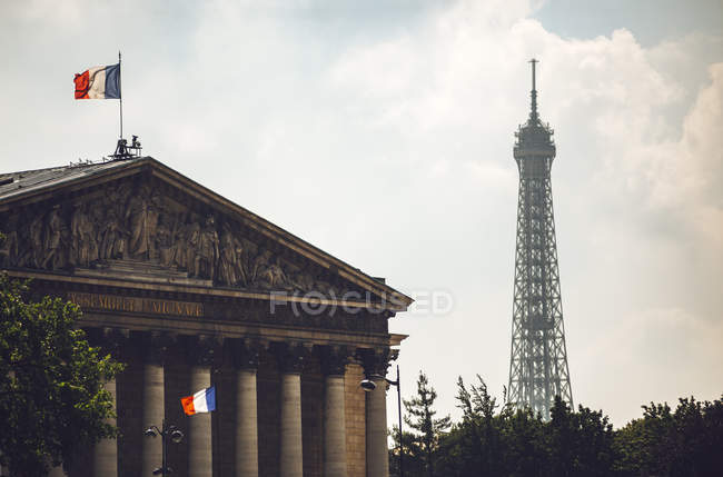Дом Парламента украшен флагами Франции на фоне Эйфелевой башни, Париж, Франция — стоковое фото
