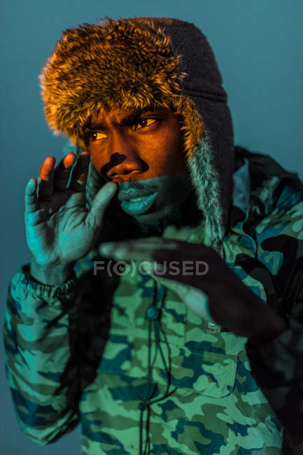 Handsome black man in warm clothes and hat with orange color on face — Stock Photo