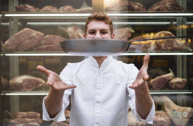 Chef cook in glasses and white gown throwing up frying pan working in restaurant. — Stock Photo