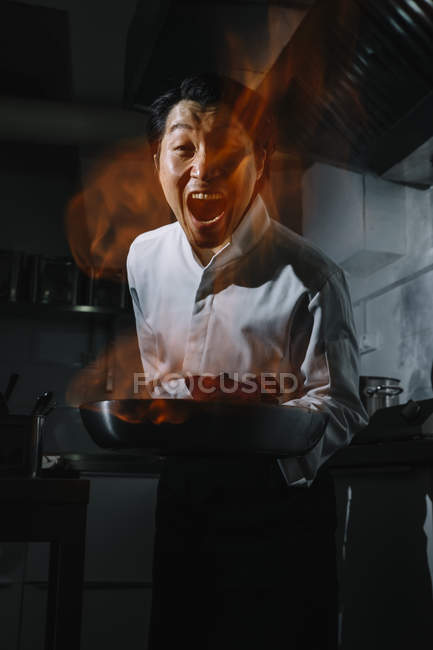 Cozinheiro animado fazendo um flambe na cozinha do restaurante — Fotografia de Stock