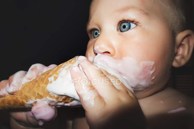 Carino bambino con faccia sporca mangiare gelato in cono cialda. — Foto stock