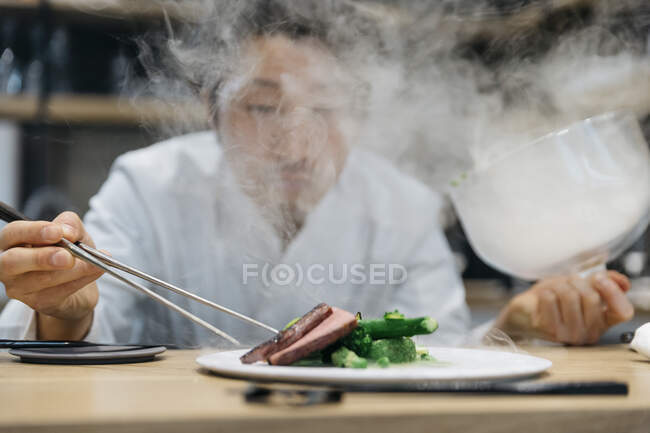 Chef cuisinier au restaurant avec plat fumé — Photo de stock