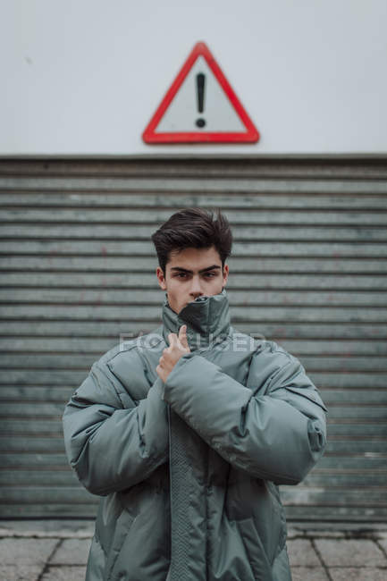 Retrato de Adolescente en chaqueta gris cálido de pie bajo el cartel en la calle - foto de stock