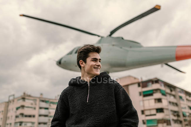 Laughing young man standing at helicopter monument on city street — Stock Photo