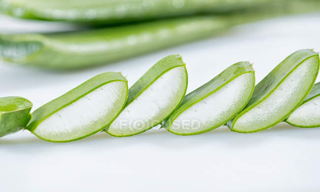 Morceaux d'Aloe Vera vert frais en rangée sur fond blanc — Photo de stock