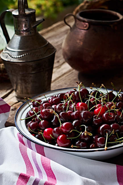 Fresh cherries in metal bowl on brown wooden table — Stock Photo