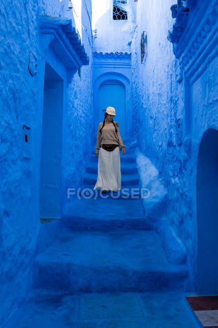 Frau mit Mütze und langem Rock läuft auf marokkanischer Stadt blau gefärbt — Stockfoto