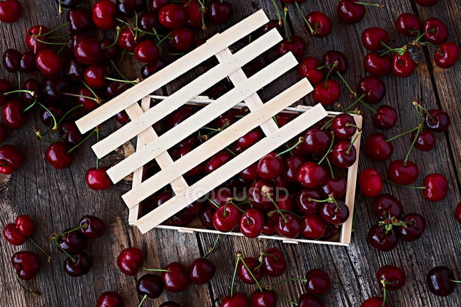 Caja de madera de deliciosas cerezas maduras sobre madera marrón - foto de stock