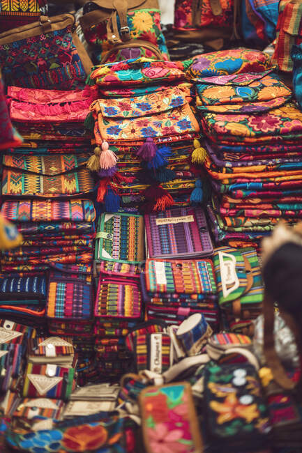 Stapelweise schöne helle Taschen und Geldbörsen liegen auf dem Marktstand in San Cristobal de las Casas in Chiapas, Mexiko — Stockfoto
