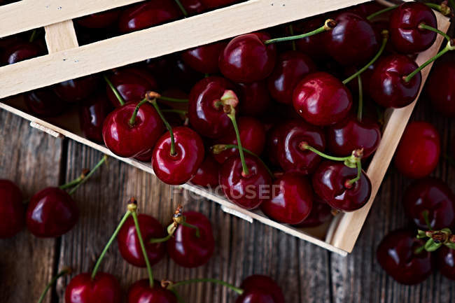 Wooden box of delicious ripe cherries on brown wood — Stock Photo