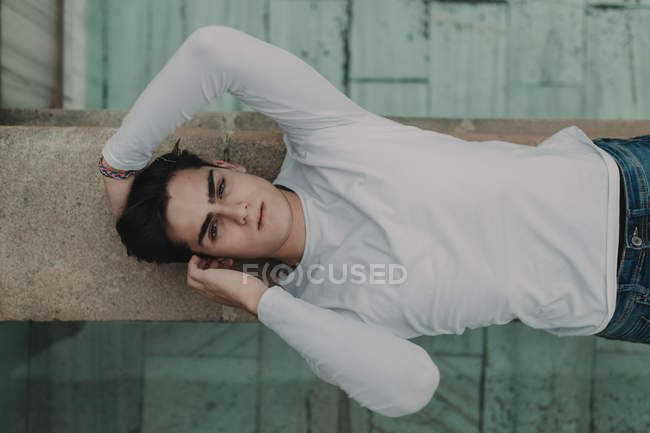 Young handsome man lying on concrete wall — Stock Photo