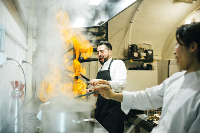Cook making flambe in restaurant kitchen — Stock Photo