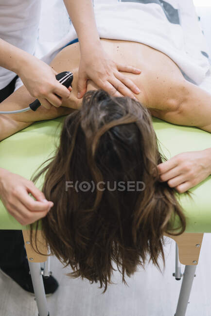 O fisioterapeuta que trata uma mulher usando equipamentos para radioterapia — Fotografia de Stock