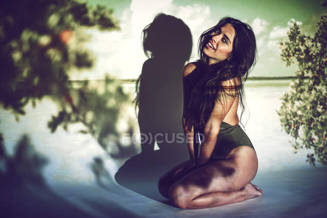 Young woman in swimming suit sitting in studio on background of sea — Stock Photo